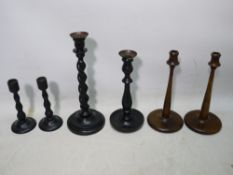 A collection of candlesticks comprising a small, turned wood ebonised pair,