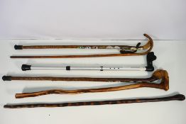 A collection of walking sticks, predominantly wooden,