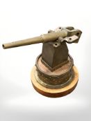 A brass model of a naval gun on circular wooden plinth, height 25cm.