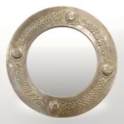 An Arts and Crafts brass porthole-shaped mirror, with Celtic knot border and bevelled plate,