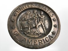 An American embossed metal wall plate, diameter 22.5 cm.