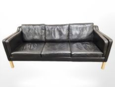 A late 20th century Danish black leather three seater settee on wooden legs,