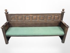 A stained pine bench with upholstered seat,