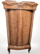 An early 20th century continental bow-front single door cabinet with pillar supports,