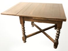 An Edwardian oak barley twist pull out extending dining table, width 86 cm.