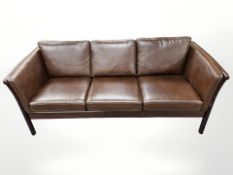 A late 20th century Danish stained wood and chestnut brown stitched leather three seater settee,