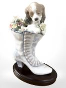 A Lladro figure of a puppy and flowers in a healed boot, on plinth, height 21.