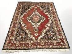 An Iranian woolen rug on red ground, 230 cm x 170 cm.