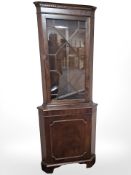 A glazed mahogany standing corner cabinet