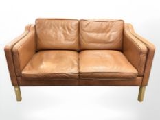 A late 20th century Danish tan leather two seater settee on oak legs,