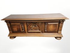 A 20th century continental carved and panelled oak low sideboard on bulbous feet,