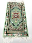 An Eastern woolen rug on green ground,