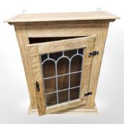 A 20th century blonde oak wall cabinet with leaded glass door,