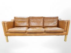 A late 20th century Danish tan leather three seater settee on oak legs,