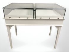 A painted shop display cabinet with two glazed lockable drawers,