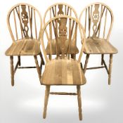 A set of four blonde oak wheel back dining chairs.