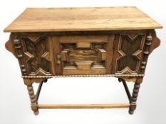 A carved oak single door side table,