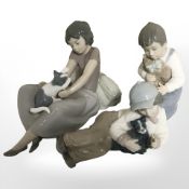 Two Nao figures of boys and a further figure of a girl playing with a kitten.