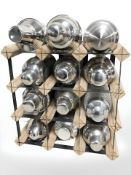 A bottle rack and twelve various cocktail shakers.