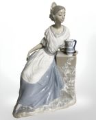 A Nao figure of a lady seated by a stone pillar, height 31 cm.