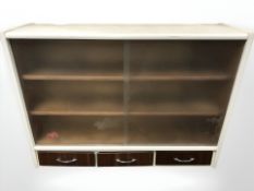 A vintage sliding glass door wall cabinet, fitted three drawers beneath, width 102 cm.