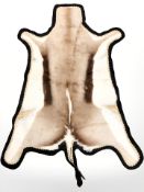 A deer skin rug, 131 cm x 100 cm.
