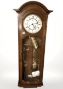 A mahogany wall clock with pendulum and key,