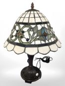 A patinated metal table lamp with tiffany style leaded glass shade, height 50 cm.