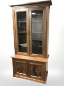 A glazed mahogany double door bookcase, 110 cm x 50 cm x 213 cm.
