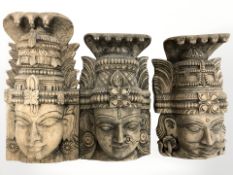 Three oriental carved wooden wall masks, largest 38 cm long.