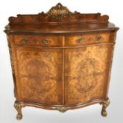A reproduction burr walnut veneered serpentine front double door cabinet on gilt lion paw feet,
