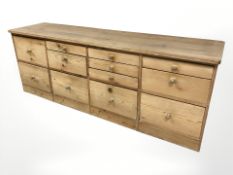 A 19th century pine twelve drawer side board, 220 cm x 56 cm x 81 cm.