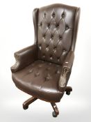 A brown buttoned and studded leather swivel office armchair.