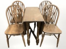An oak drop leaf table and four wheel back chairs