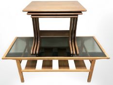 A teak nest of three tables, width 56 cm, and a further smoked glass topped coffee table.