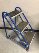 A three tread step on castors, height 79 cm.