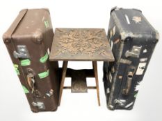 A carved oak occasional table and two vintage suitcases.