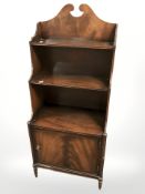A reproduction mahogany waterfall bookcase with cabinet beneath, 46 cm wide.