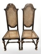 A pair of Edwardian oak and canework high backed chairs.