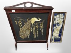 A mahogany embroidered fire screen depicting a peacock,