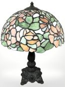 A patinated metal table lamp with Tiffany style leaded glass mushroom shade, height 52 cm.