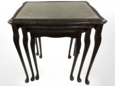 A reproduction nest of three shaped occasional tables with tooled leather inset tops, width 54 cm.