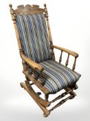 A carved beech rocking chair in striped upholstery.