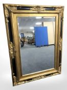 A reproduction ebonised and gilt over mantle mirror, 122 cm x 90 cm.