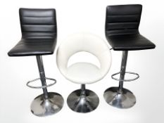 A pair of chrome and black vinyl rise and fall bar chairs, and a further cream chair.