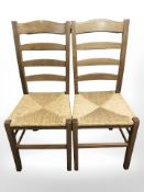 A pair of ladderback dining chairs with rattan seats.