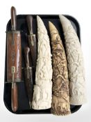 A group of Eastern carving knives in wooden sheathes and three resin tusk-style ornaments.