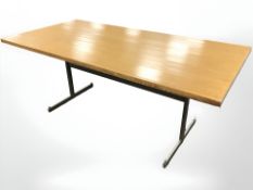 An oak veneered dining table on metal supports,