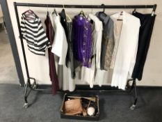 A rail of lady's clothing, leather hand bags, etc.