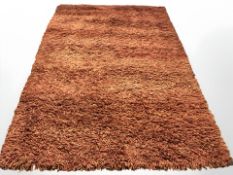 A shaggy pile rug on orange ground, 275 cm x 184 cm.